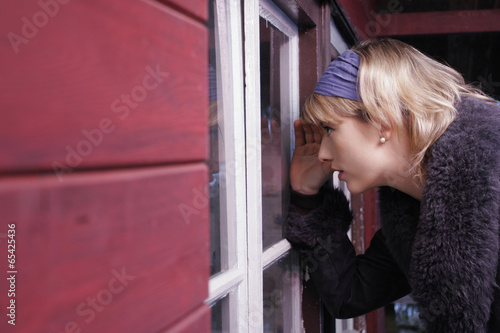Photo: Junge Frau schaut durch Fenter in ein Haus Junge Frau schaut durch Fenter in ein Haus