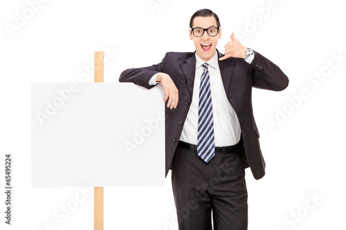 Photo: Businessman standing by a blank banner Businessman standing by a blank banner