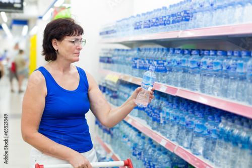 Photo: woman buys a bottle of water in the store woman buys a bottle of water in the store