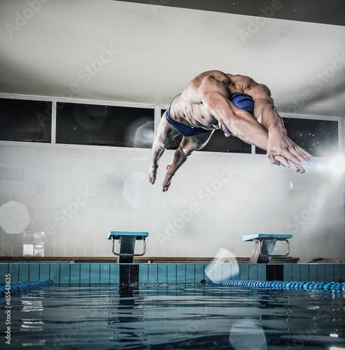 Photo: Young muscular swimmer jumping from starting block Young muscular swimmer jumping from starting block