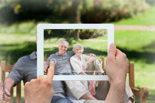 Photo: Composite image of hand holding tablet pc Composite image of hand holding tablet pc