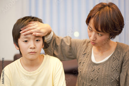 Photo: 中学生の息子の熱を確認する母親 中学生の息子の熱を確認する母親