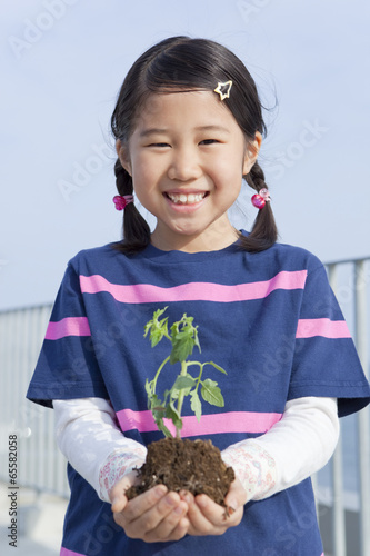 Photo: 植物の苗を持って立つ女の子 植物の苗を持って立つ女の子