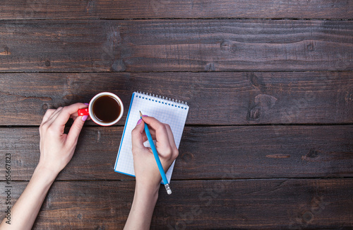 Photo: Hands holding notebook and coffee cup. Hands holding notebook and coffee cup.