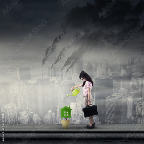 Photo: Businesswoman watering plant on rooftop Businesswoman watering plant on rooftop