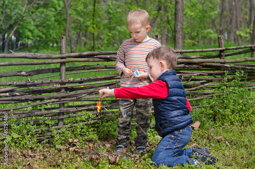 Photo: Two small boys lighting a fire in woodland Two small boys lighting a fire in woodland