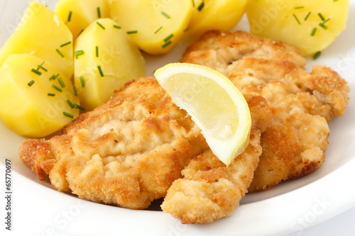 Photo: Golden fried schnitzel with boiled potatoes, chives and lemon. Golden fried schnitzel with boiled potatoes, chives and lemon.