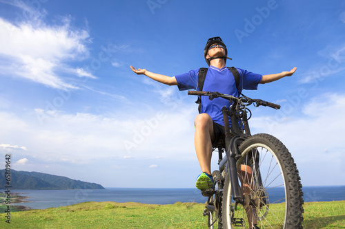 Photo: young man sitting on a mountain bike and open arms to relaxing young man sitting on a mountain bike and open arms to relaxing