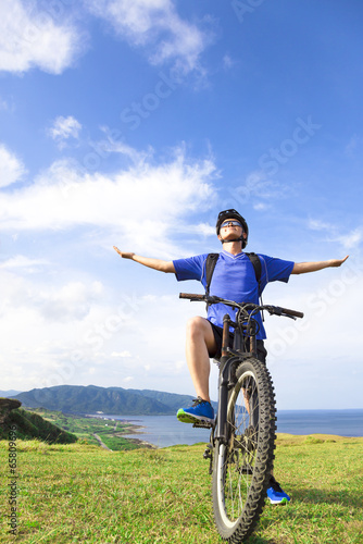 Photo: young backpacker sitting on a mountain bike and relaxing pose young backpacker sitting on a mountain bike and relaxing pose