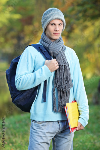 Photo: Male student holding books on a cold day in park Male student holding books on a cold day in park