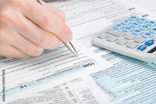 Photo: USA Tax Form 1040 - man filling out tax form USA Tax Form 1040 - man filling out tax form