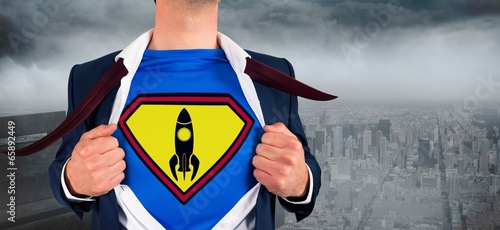 Photo: Composite image of businessman opening shirt in superhero style Composite image of businessman opening shirt in superhero style