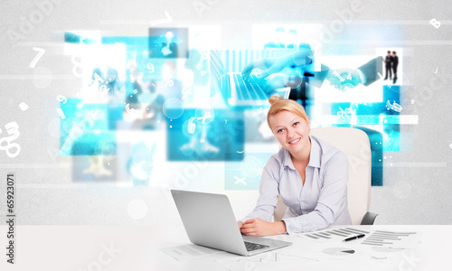 Photo: Business person at desk with modern tech images at background Business person at desk with modern tech images at background
