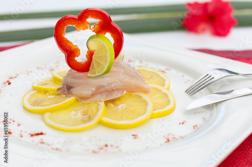 Photo: Fish Carpaccio on lemon, decorated with red bell pepper slice a Fish Carpaccio on lemon, decorated with red bell pepper slice a