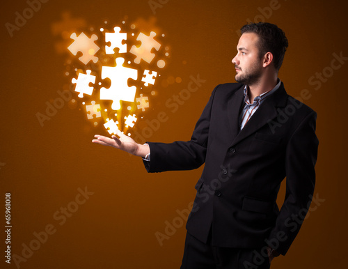 Photo: Puzzle pieces in the hand of a businessman Puzzle pieces in the hand of a businessman