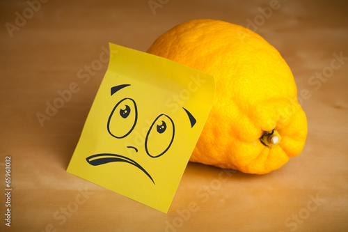 Photo: Post-it note with smiley face sticked on lemon Post-it note with smiley face sticked on lemon