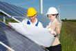 Photovoltaic engineers with construction plan at solar panels Photovoltaic engineers with construction plan at solar panels