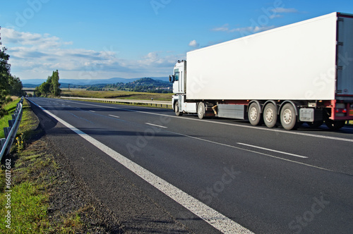 Photo: White truck driving on the road a rural landscape White truck driving on the road a rural landscape