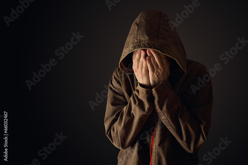 Photo: Depressive man in hooded jacket is crying Depressive man in hooded jacket is crying