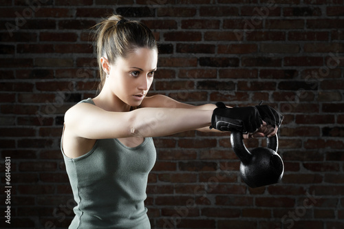 Photo: Young fit woman lifting kettle bell Young fit woman lifting kettle bell