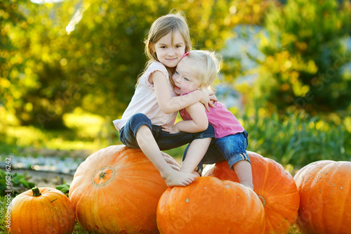 Photo: Two little sisters sitting on huge pumpkins Two little sisters sitting on huge pumpkins