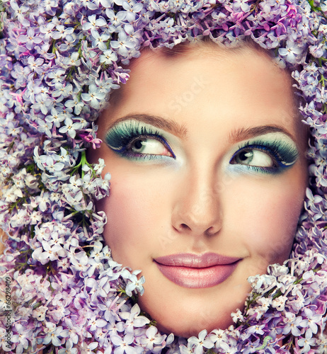 Photo: Funny beautiful model in flowers lilac sly looks in the side. Funny beautiful model in flowers lilac sly looks in the side.