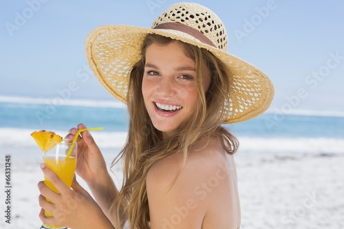 Photo: Pretty smiling blonde in bikini holding cocktail on the beach Pretty smiling blonde in bikini holding cocktail on the beach