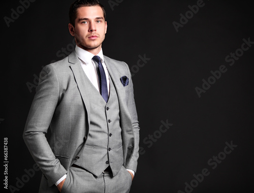 Photo: Handsome young business man standing on black background Handsome young business man standing on black background