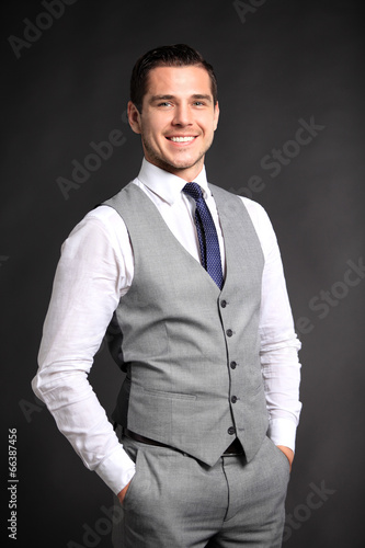 Photo: Handsome young business man standing on black background Handsome young business man standing on black background