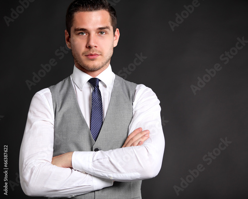 Photo: Handsome young business man standing on black background Handsome young business man standing on black background