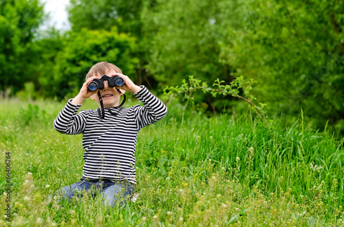 Photo: Little boy looking at the camera with binoculars Little boy looking at the camera with binoculars