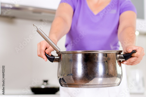 Photo: Woman holding out a metal saucepan Woman holding out a metal saucepan