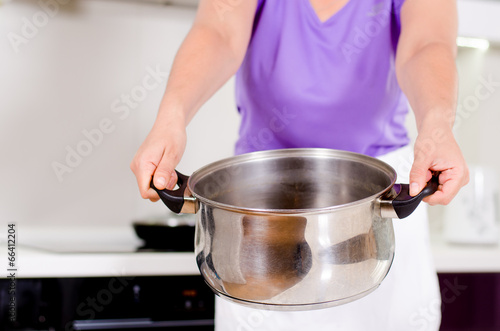 Photo: Woman holding out a metal saucepan Woman holding out a metal saucepan