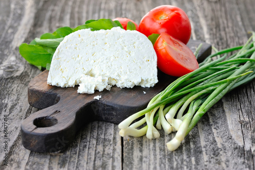 Photo: Cheese with tomatoes and arugula and onion on a wooden board Cheese with tomatoes and arugula and onion on a wooden board