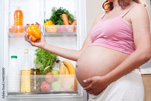 Photo: pregnant woman and refrigerator with health food vegetables pregnant woman and refrigerator with health food vegetables