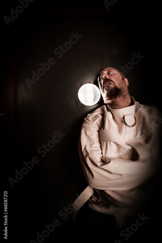 Photo: Crazy person in a cell wearing a straitjacket Crazy person in a cell wearing a straitjacket