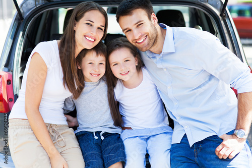 Photo: Happy family of four sitting in car trunk Happy family of four sitting in car trunk