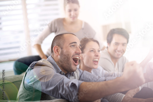 Photo: Cheerful group of friends watching football game on tv Cheerful group of friends watching football game on tv