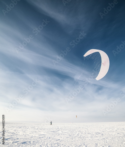 Photo: Kiteboarder with blue kite on the snow Kiteboarder with blue kite on the snow