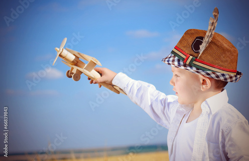 Photo: Serious little boy playing with a toy airplane Serious little boy playing with a toy airplane