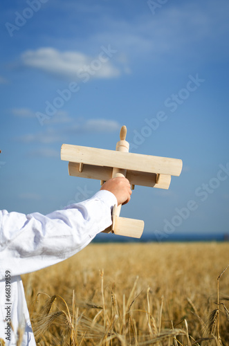 Photo: Little boy playing in farmland with a toy airplane Little boy playing in farmland with a toy airplane
