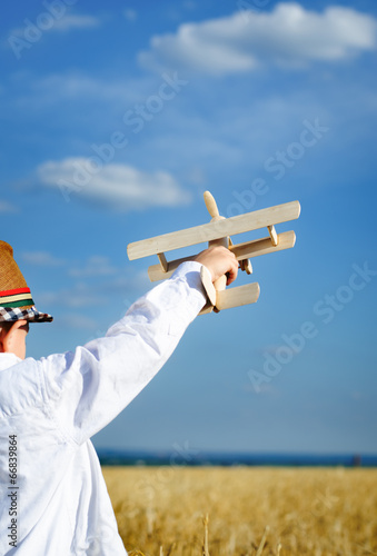 Photo: Little boy playing in farmland with a toy airplane Little boy playing in farmland with a toy airplane
