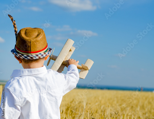 Photo: Cute little boy flying his toy biplane Cute little boy flying his toy biplane