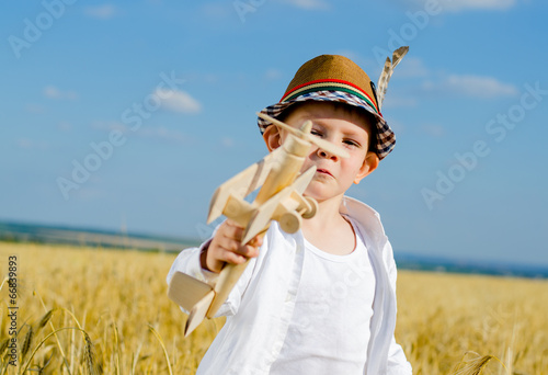 Photo: Cute little boy flying his toy biplane Cute little boy flying his toy biplane