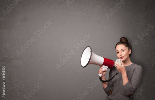 Photo: Girl shouting into megaphone on copy space background Girl shouting into megaphone on copy space background