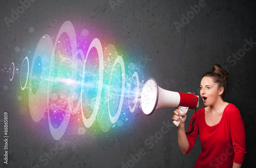 Photo: Young girl yells into a loudspeaker and colorful energy beam com Young girl yells into a loudspeaker and colorful energy beam com