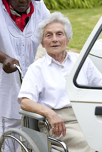 Photo: Caregiver helping disabled lady get into the car Caregiver helping disabled lady get into the car