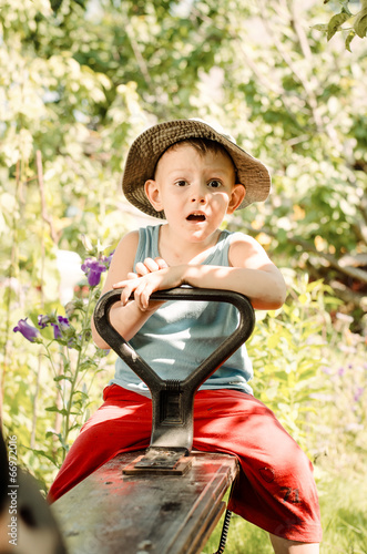 Photo: Cute little country boy sitting in a garden Cute little country boy sitting in a garden