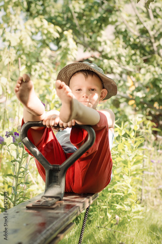 Photo: Cute little country boy sitting in a garden Cute little country boy sitting in a garden
