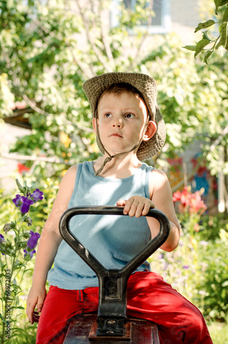 Photo: Thoughtful young boy sitting in a country garden Thoughtful young boy sitting in a country garden